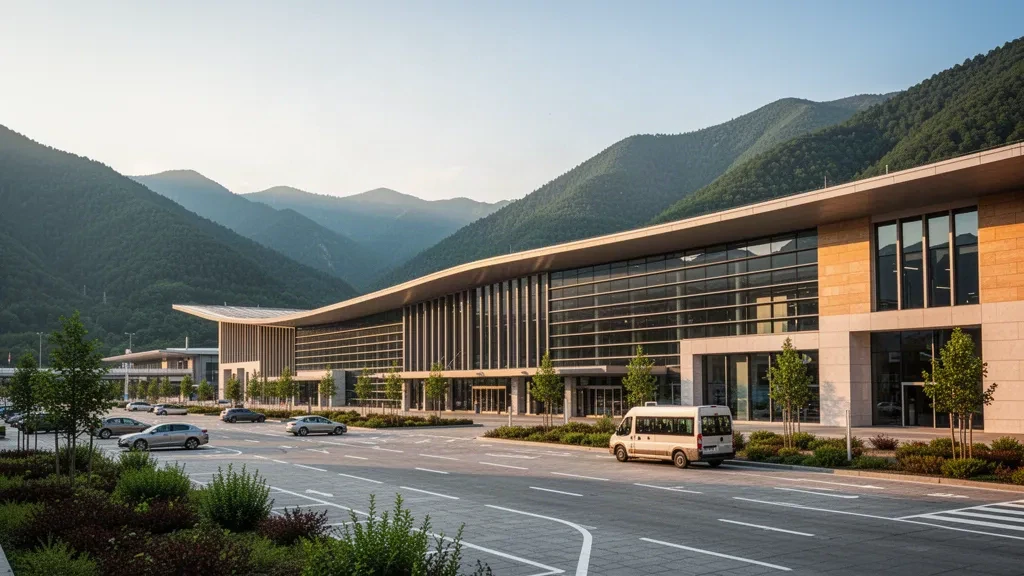Modernes Glas-Terminal des internationalen Flughafens Lachin mit Bergkulisse und leeren Vorfahrtsspuren zur goldenen Stunde