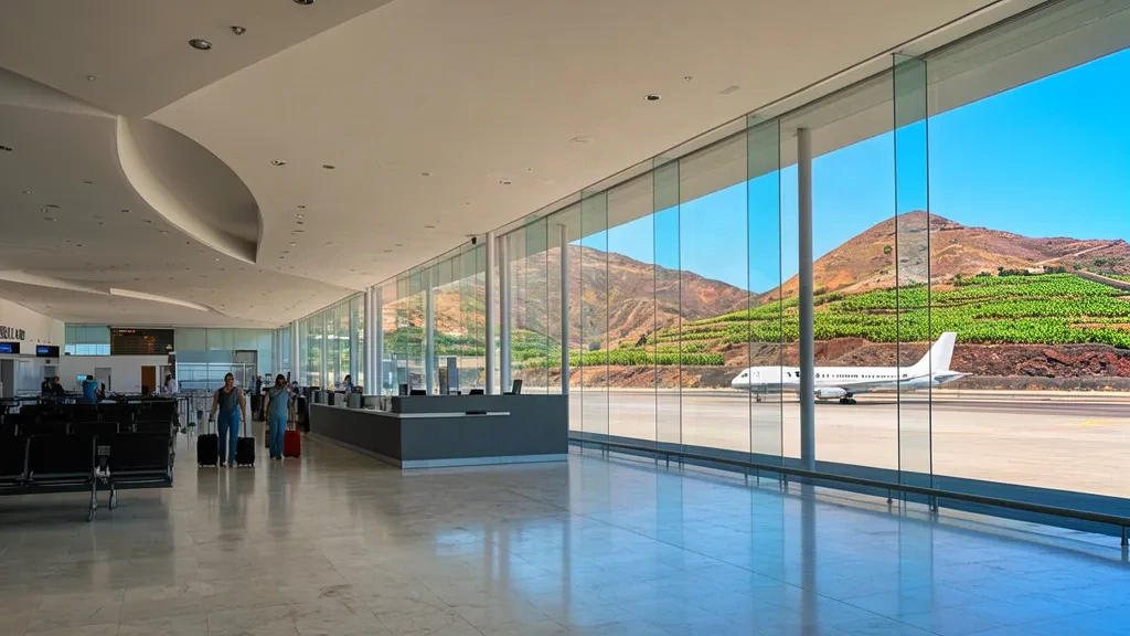 Bright interior of La Palma Airport terminal in the Canary Islands, with check-in hall, seated travellers and volcanic landscape beyond the glass