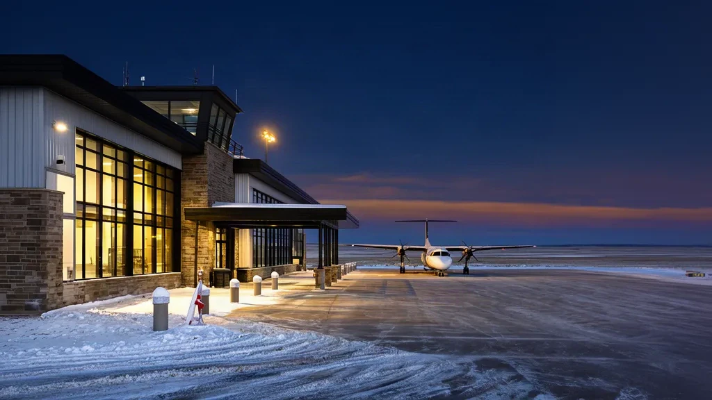 Edificio terminal bajo en el aeropuerto de Lloydminster, en la frontera entre Alberta y Saskatchewan, con un turbohélice aparcado en la plataforma al crepúsculo