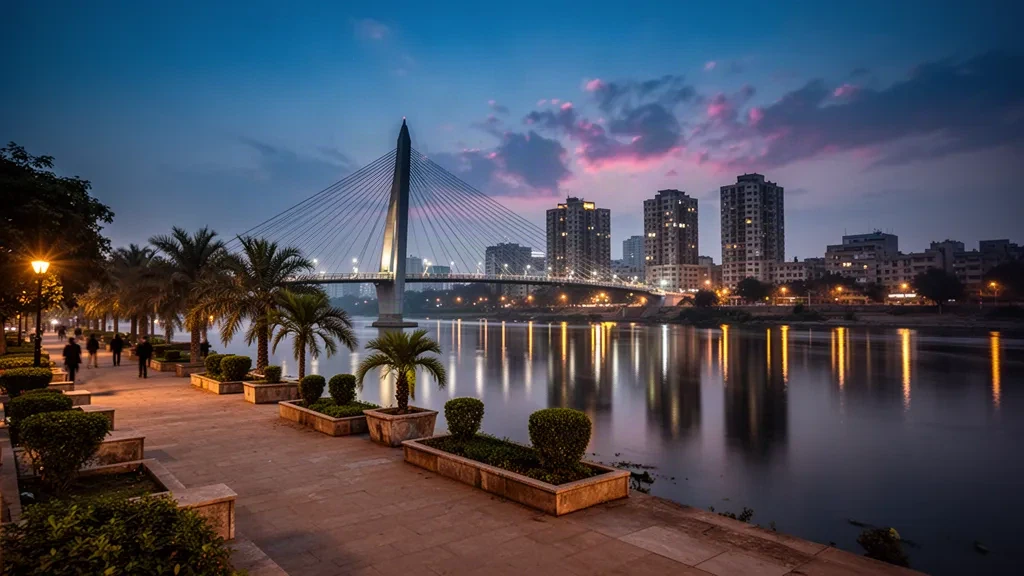Skyline von Ahmedabad entlang der Sabarmati-Uferpromenade in der Dämmerung mit der Atal-Fußgängerbrücke und warmen Stadtlichtern, die sich im Wasser spiegeln