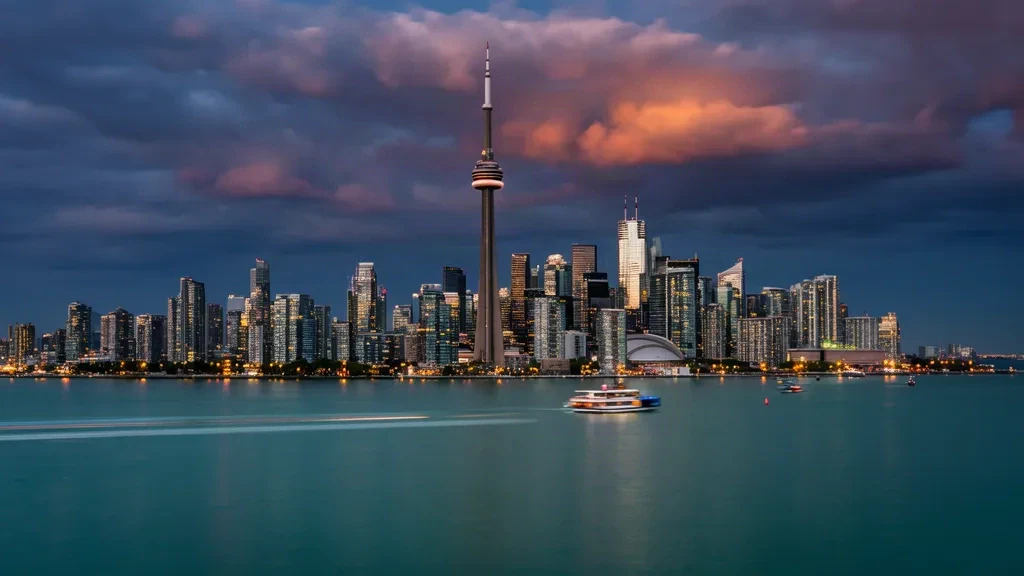 Toronto skyline with the CN Tower glowing at dusk above Lake Ontario, representing Canada as a travel destination